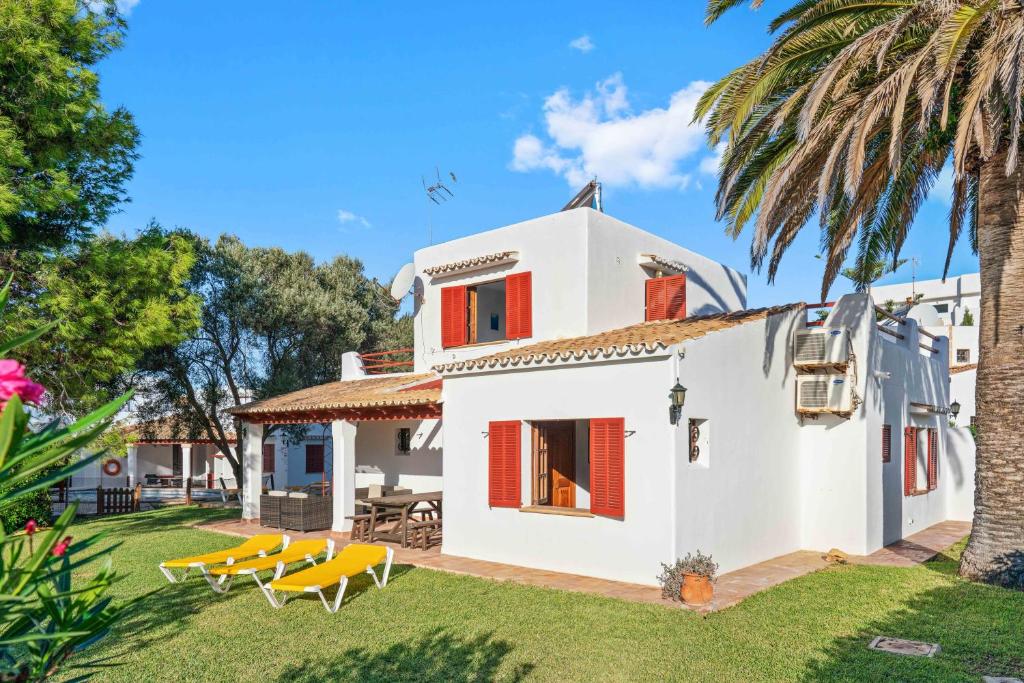 een wit huis met stoelen en een palmboom bij Villa Sa Palmera in Cala d´Or