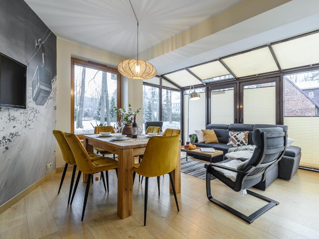 a dining room and living room with a table and chairs at VisitZakopane - Queen Apartment in Zakopane