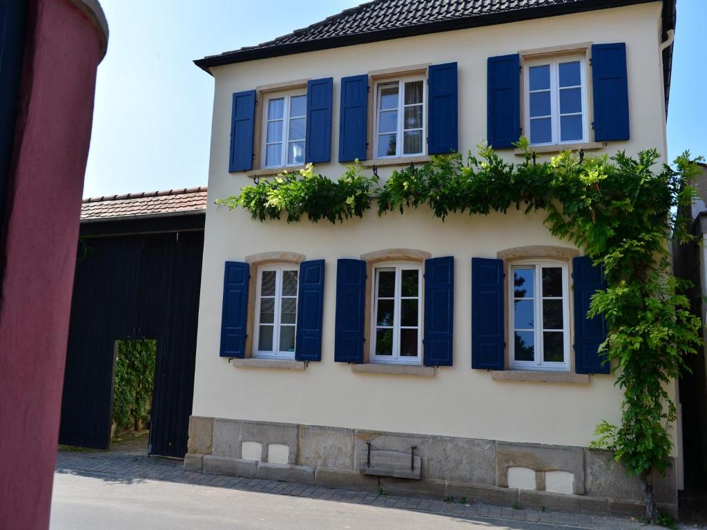 una casa con persianas azules en un edificio en Gästehaus & Weingut GEHRIG en Weisenheim am Sand