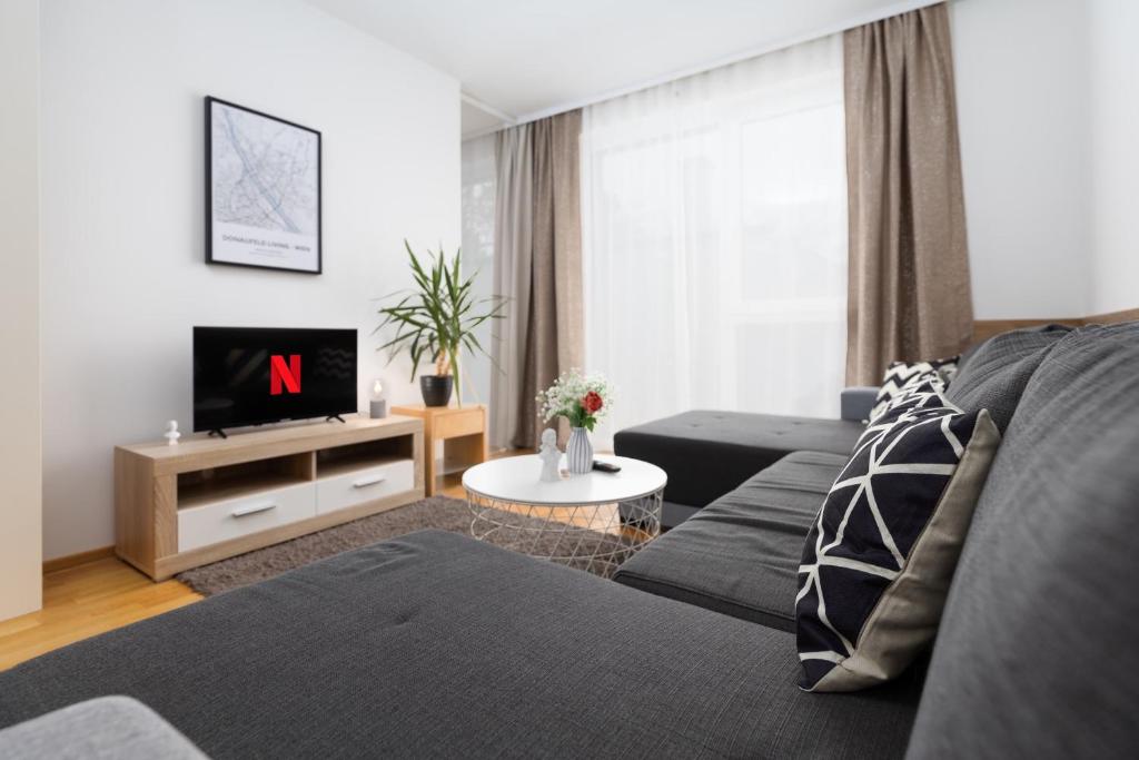 a living room with a couch and a tv at Donaufeld Living - Modernes und helles Apartment in Vienna