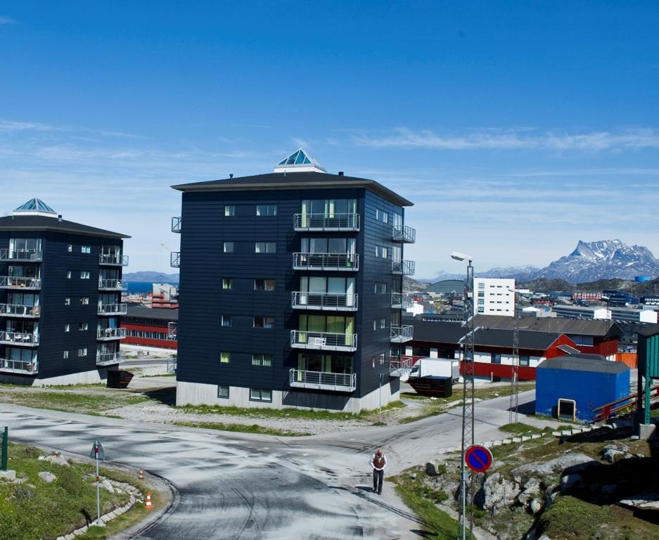 ヌークにあるNuuk Hotel Apartments by HHEの高層建築物の前に立つ者