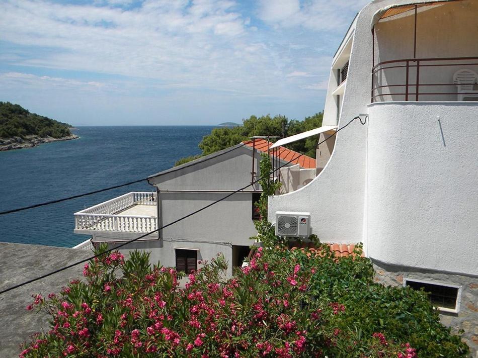 ein weißes Gebäude mit Blumen vor dem Wasser in der Unterkunft Apartments Žirje in Žirje