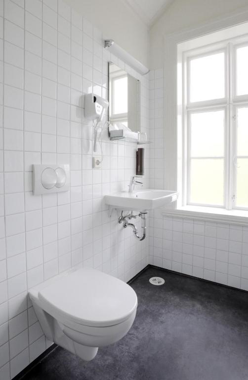 a white bathroom with a toilet and a sink at Fosshotel Eastfjords in Fáskrúðsfjörður