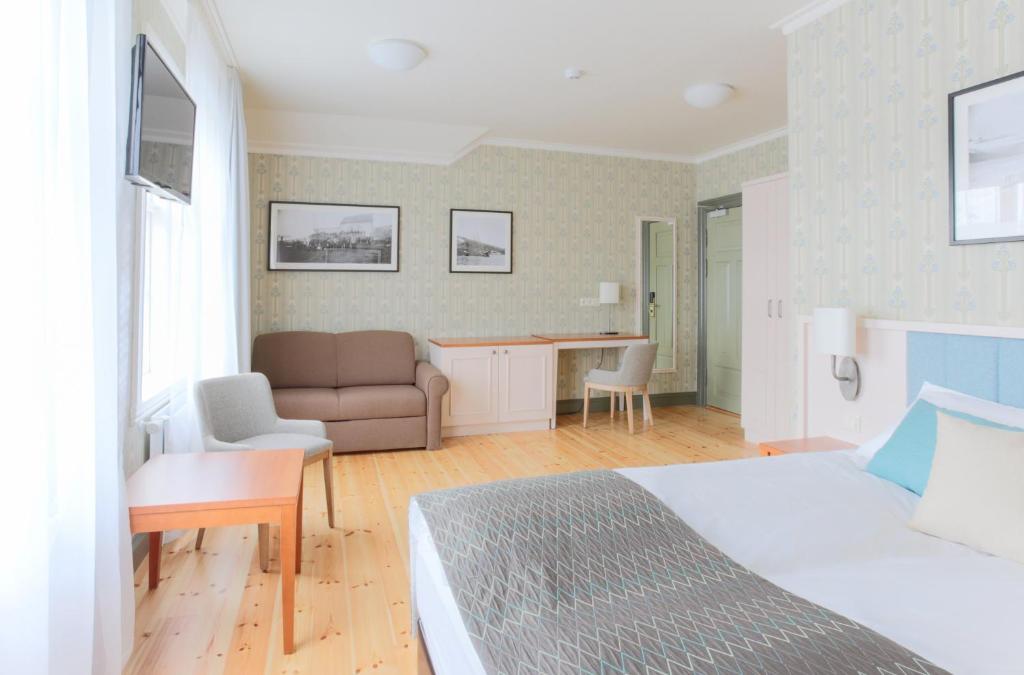 a bedroom with a bed and a desk and a couch at Fosshotel Eastfjords in Fáskrúðsfjörður
