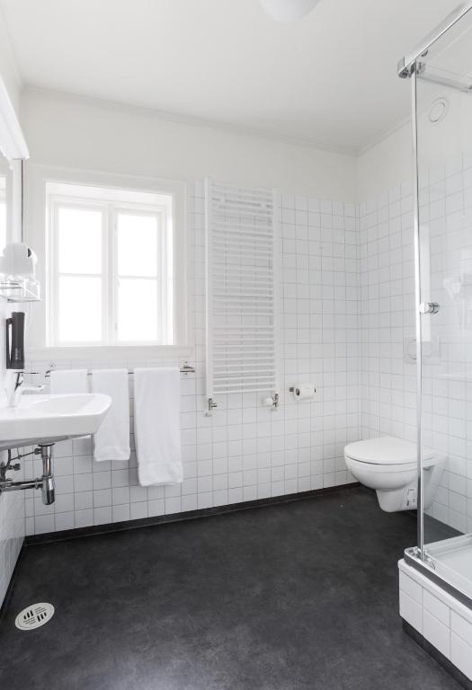a white bathroom with a toilet and a sink at Fosshotel Eastfjords in Fáskrúðsfjörður