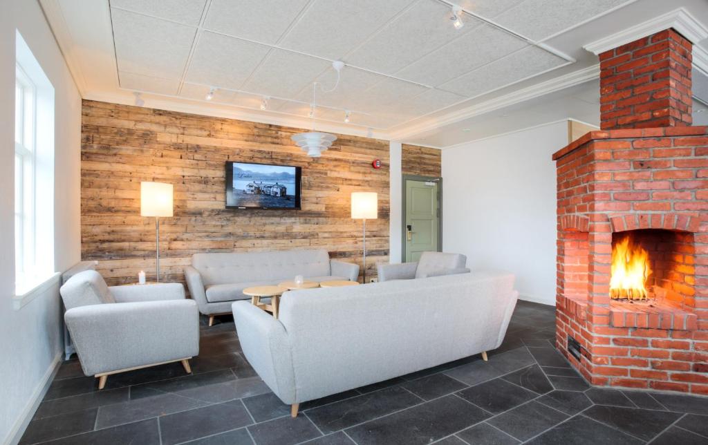 a living room with a brick fireplace and couches at Fosshotel Eastfjords in Fáskrúðsfjörður
