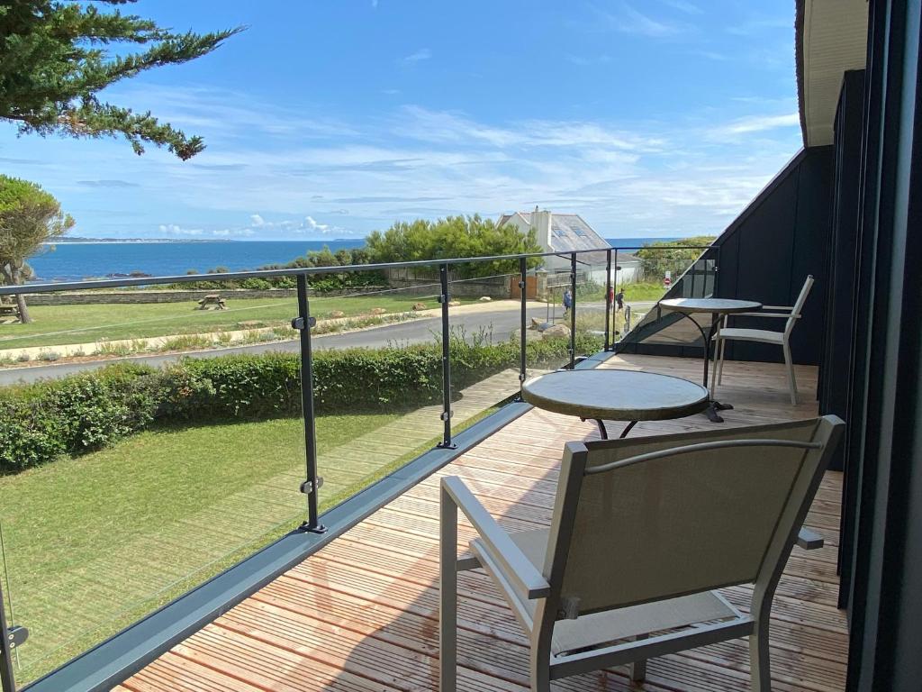 einen Balkon mit Stühlen, einem Tisch und Meerblick in der Unterkunft Les Chardonnerets - Maison contemporaine Vue Mer in Clohars-Carnoët