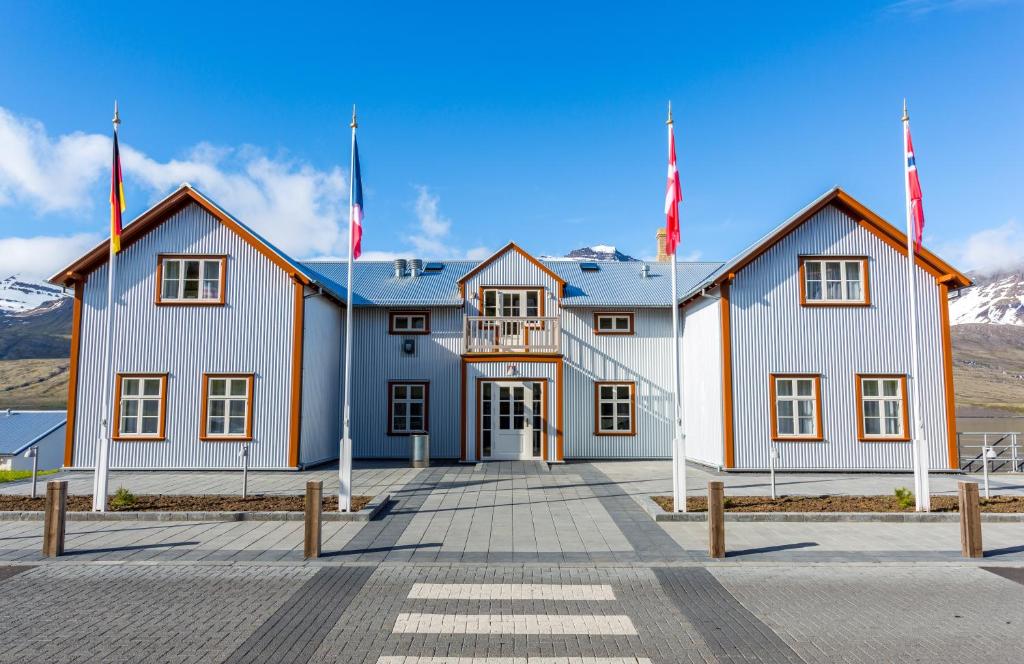 a large white building with flags in front of it at Fosshotel Eastfjords in Fáskrúðsfjörður