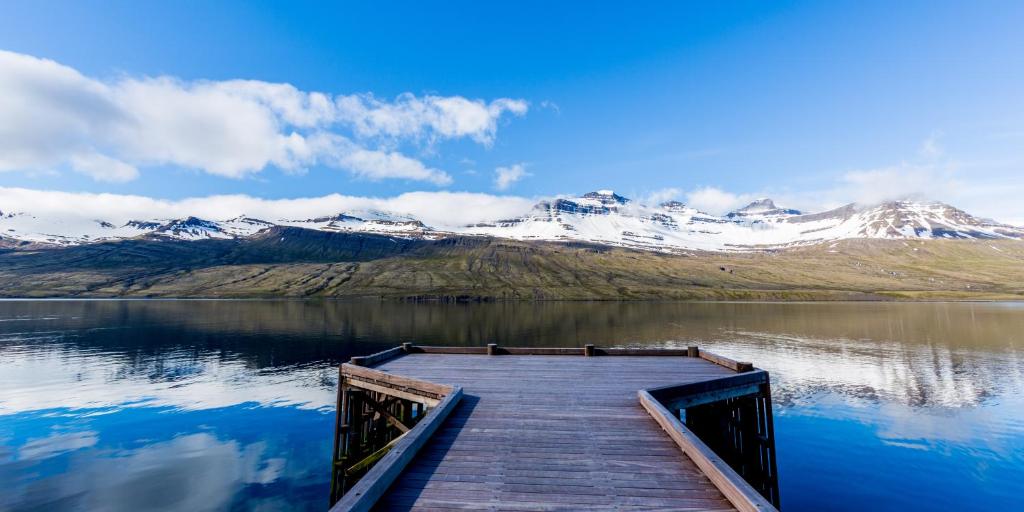a dock on a lake with snow covered mountains at Fosshotel Eastfjords in Fáskrúðsfjörður