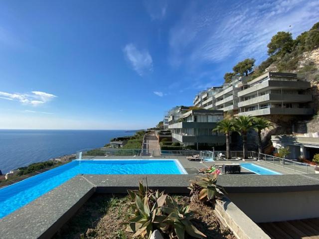 a swimming pool in front of a building next to the ocean at Unique Apartment - Costa Plana in Cap d'Ail