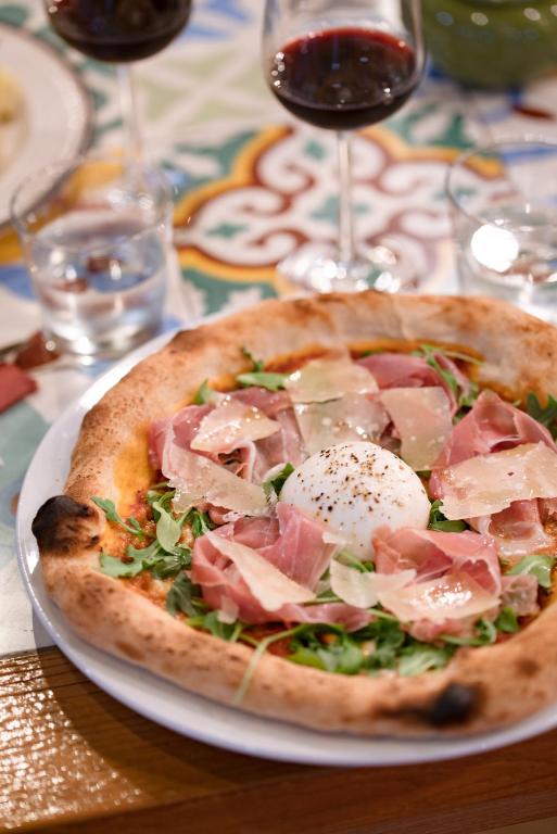 a pizza on a plate on a table with wine glasses at Blue Sail Hotel in Anse Marcel 