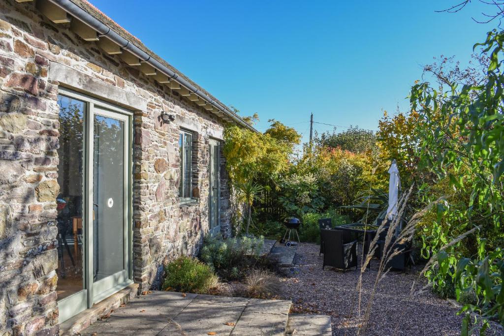 a brick house with a window and a patio at Bradbridge Barn in Newton Ferrers