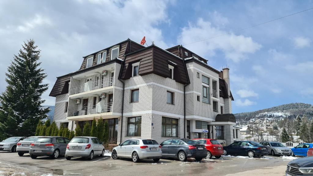 un gran edificio con coches estacionados en un estacionamiento en Hotel Damis, en Pale