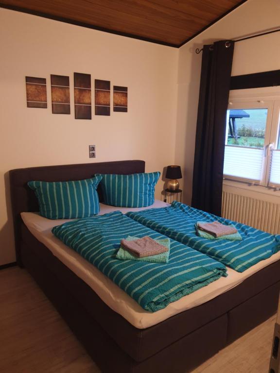 Schlafzimmer mit einem Bett mit blauer Bettwäsche und einem Fenster in der Unterkunft Ferienhaus Bella in Willingen