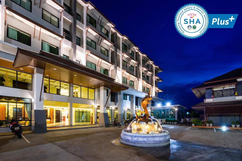 a hotel with a fountain in front of a building at Pura Nakhon Hotel in Nakhon Si Thammarat