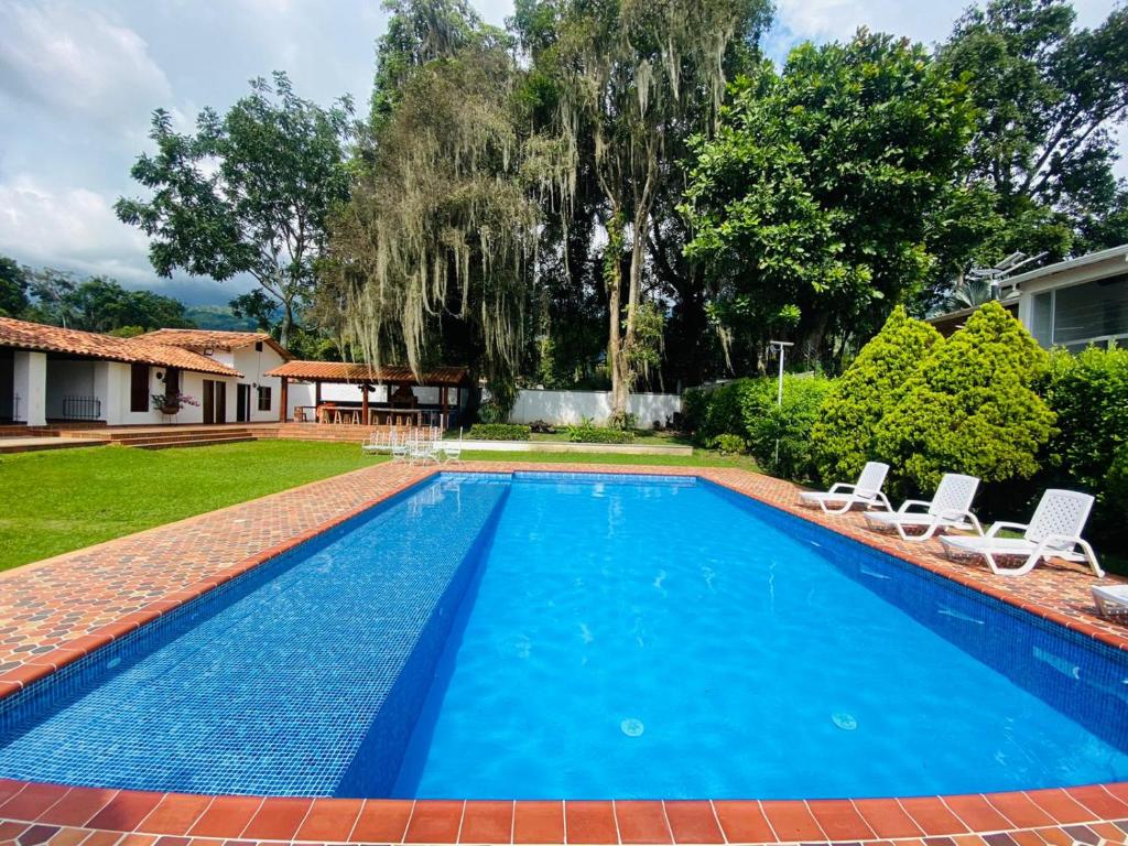 a swimming pool with two chairs and a house at Hotel Casa Blanca Campestre in La Mata