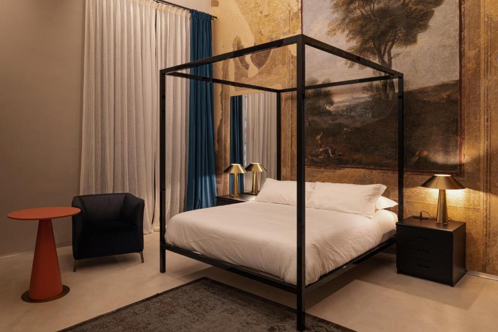 a bedroom with a four poster bed and a chair at Casa Conoscenti Suites in Bologna