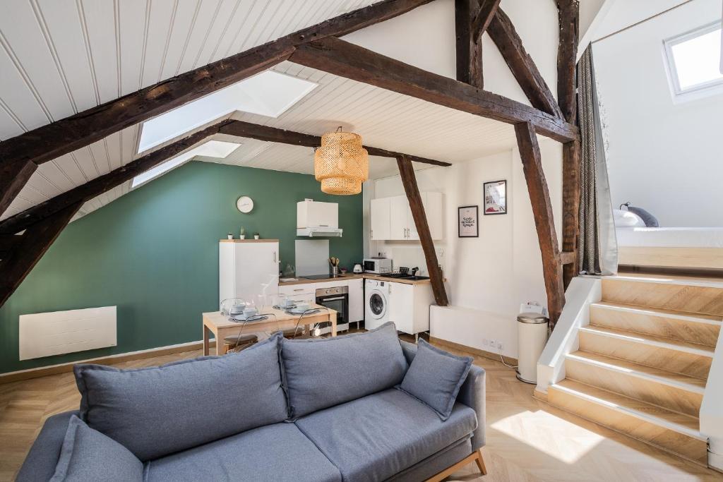 un salon avec un canapé bleu et une cuisine dans l'établissement LE PETIT MARIUS - Cocon au cœur du centre-ville historique, à Rennes