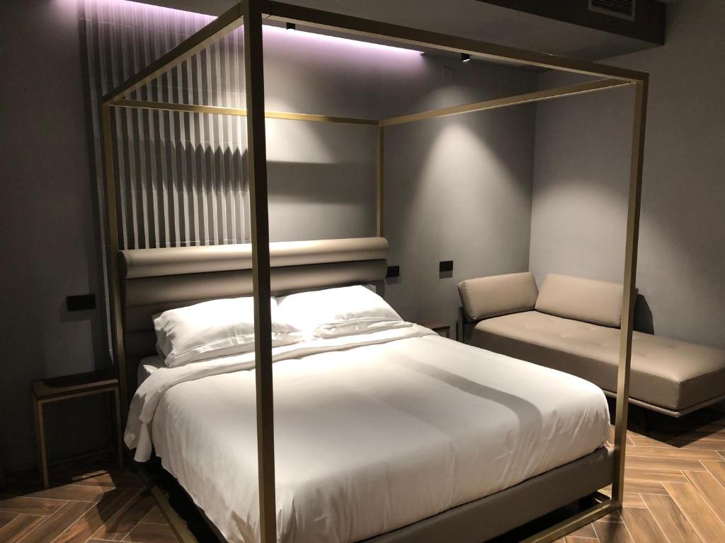 a bedroom with a canopy bed and a chair at Materiaprima camere-rooms in Mantova