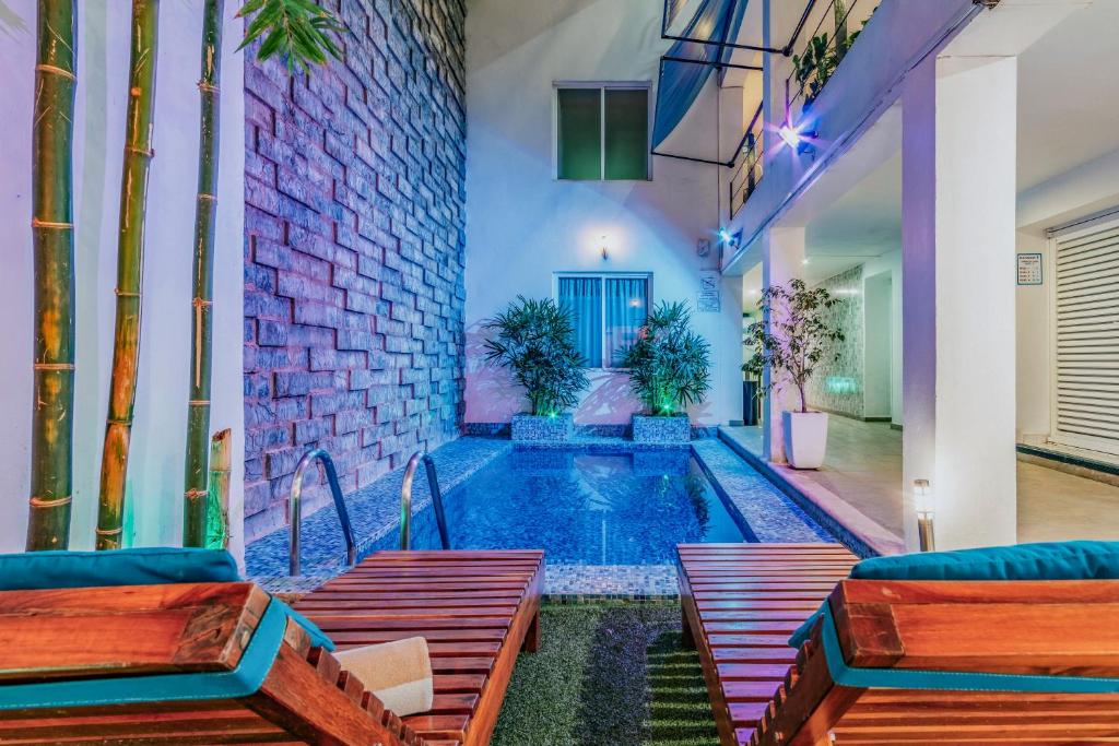 梅里達的住宿－Hotel Eclipse Mérida，一座带长椅的建筑中间的游泳池