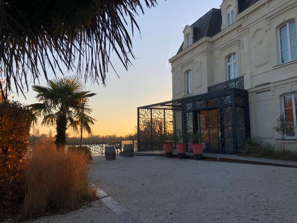 un grand bâtiment blanc avec un palmier en face dans l'établissement Les 3 Lieux, à Les Ponts-de-Cé