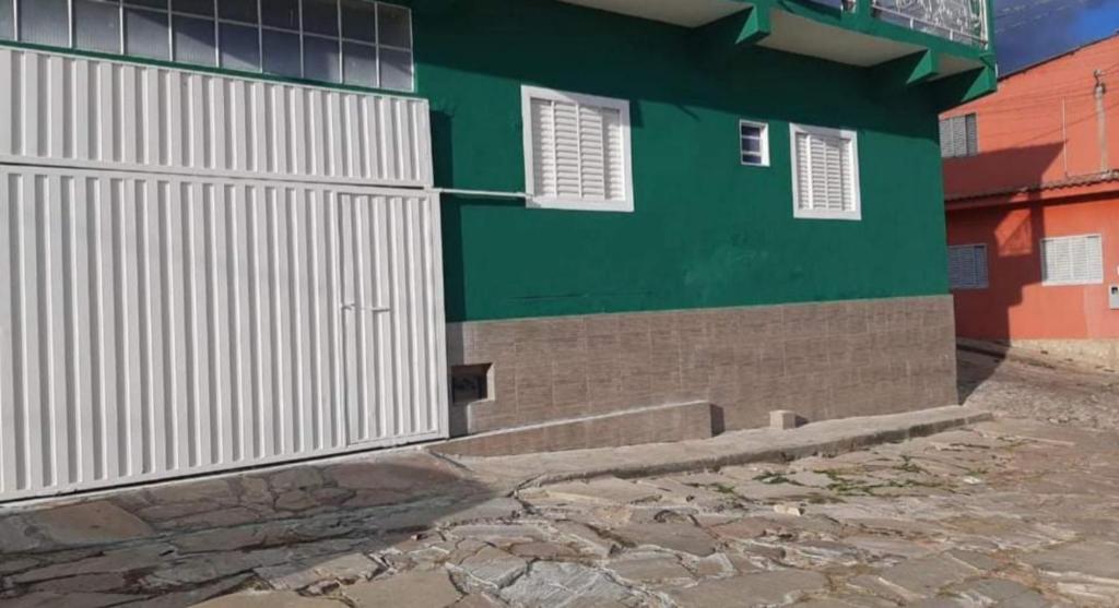 um edifício verde e branco com um portão em Casa Magnificat em São Tomé das Letras