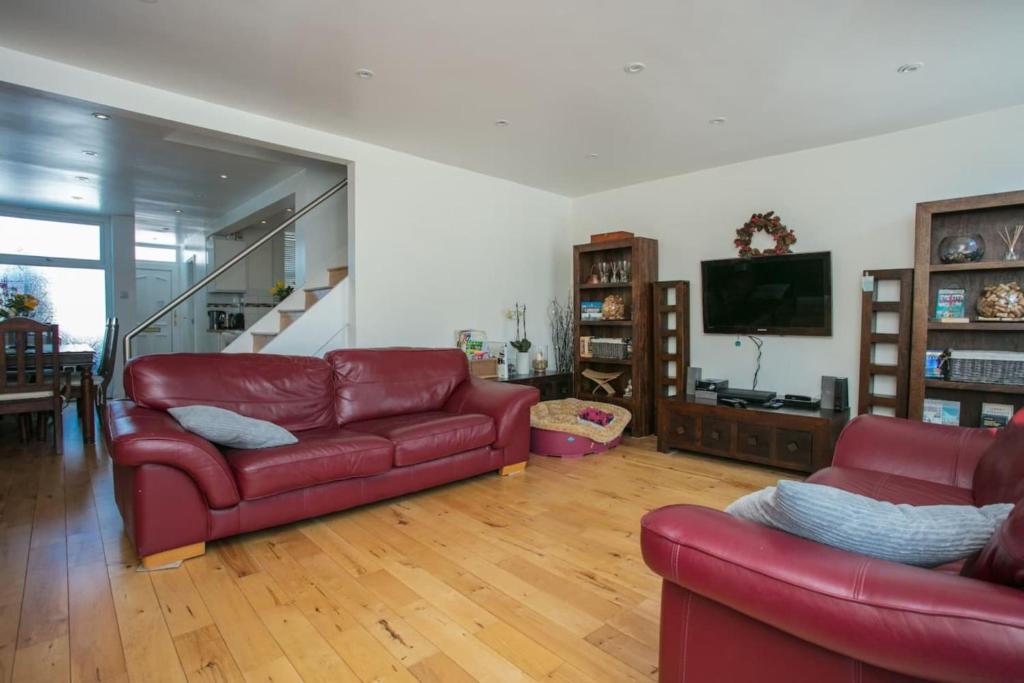 uma sala de estar com dois sofás vermelhos e uma televisão em Stunning 3 Bedroom House with Garden in Battersea em Londres