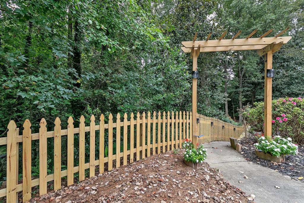 a wooden fence with a gazebo and flowers at Nature Lover Minimalist APT In Tranquil Cul De Sac in Decatur