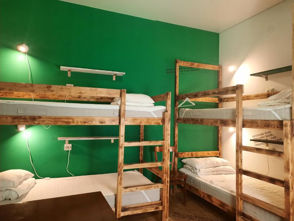 a room with three bunk beds and a green wall at Academy of Hostel in Kostroma