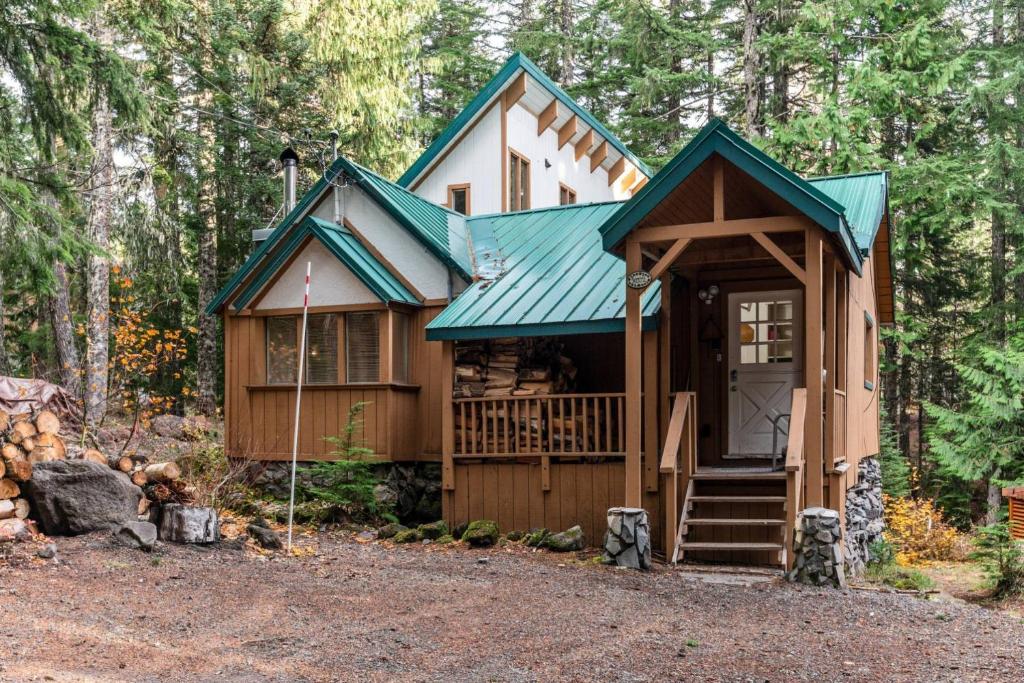 una pequeña casa en el bosque con un techo verde en Tom Creek Haus, en Government Camp