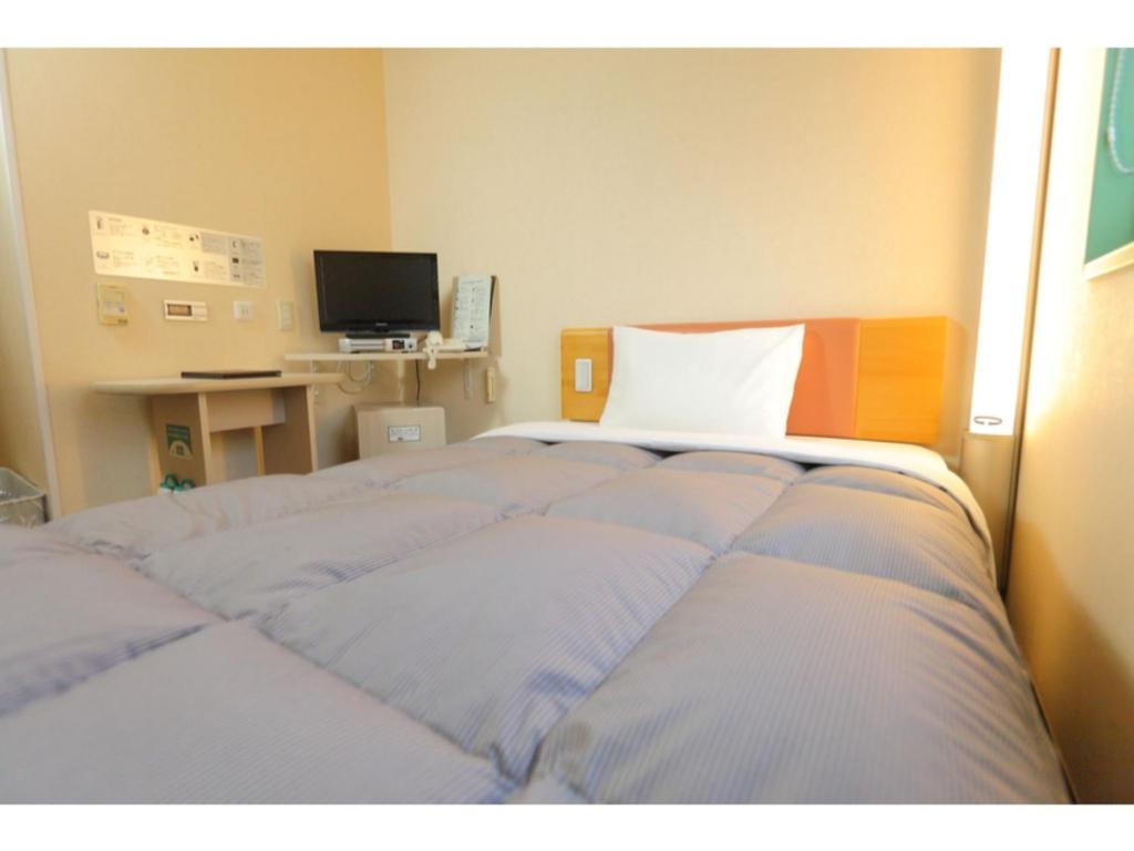 a bedroom with a bed and a desk with a television at R&B Hotel Sapporo Kita 3 Nishi 2 - Vacation STAY 39504v in Sapporo