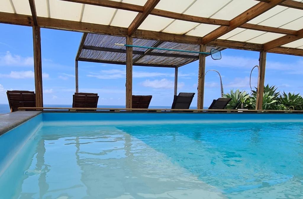 a swimming pool with chairs and the ocean in the background at Quinta da Meia Eira in Castelo Branco