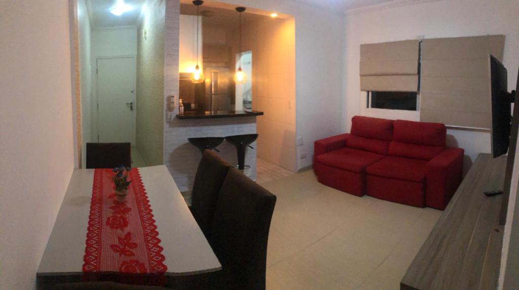 - un salon avec une table et un canapé rouge dans l'établissement apartamento próximo a praia da Enseada, à Guarujá