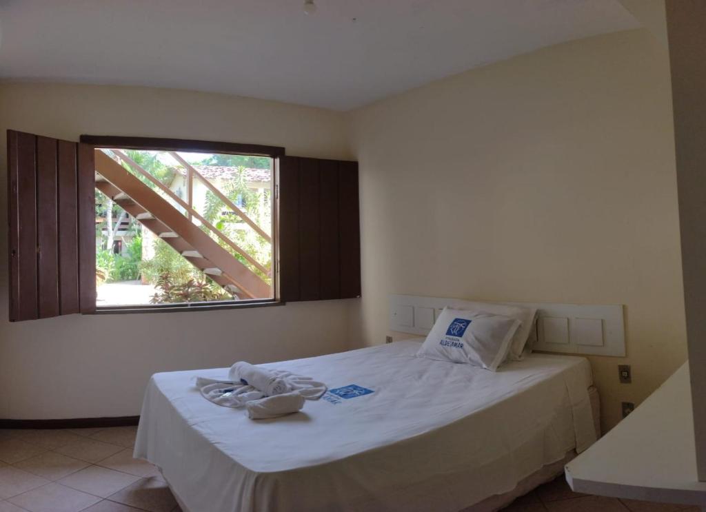 Un dormitorio con una cama grande con ventana. en Pousada Aldeia Mar, en Ilhéus