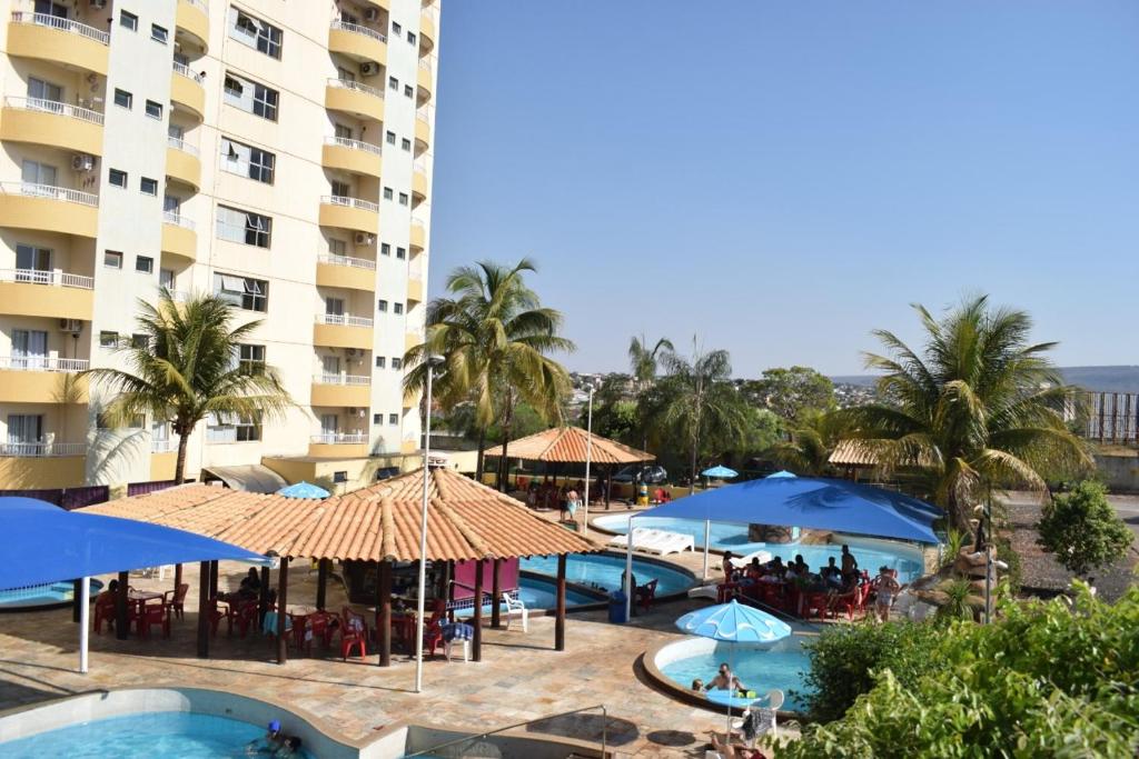 a hotel with a pool and tables and umbrellas at Suíte Thermas Place in Caldas Novas