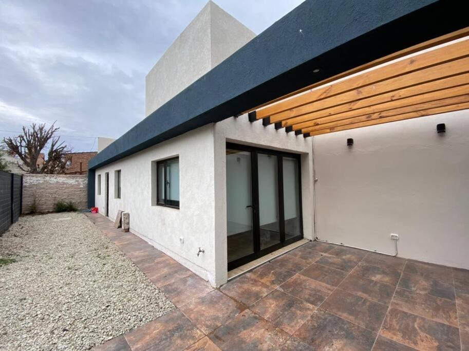 a white building with a black roof and a patio at Casa San Benito in Trelew