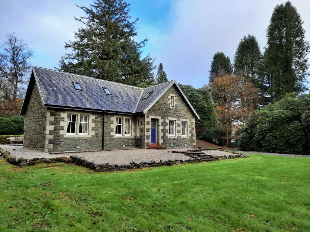 ein Steinhaus mit einem großen Hof in der Unterkunft Penninghame West Lodge in Newton Stewart