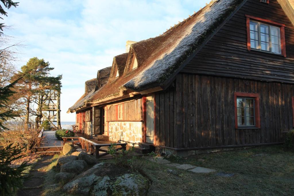 uma casa com telhado de palha e um banco no exterior em Tuulingu Guest House at Matsalu National Park em Haeska