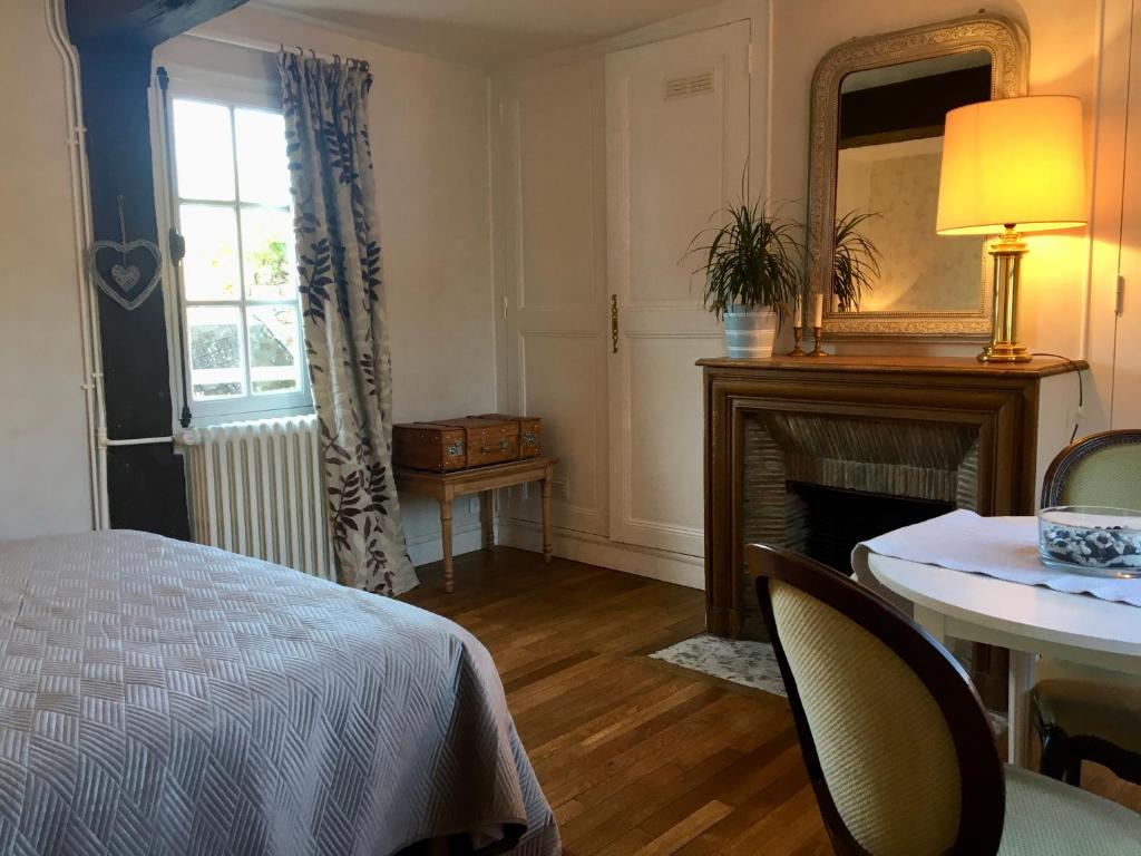 een slaapkamer met een bed, een tafel en een spiegel bij La petite duchesse in Vernon