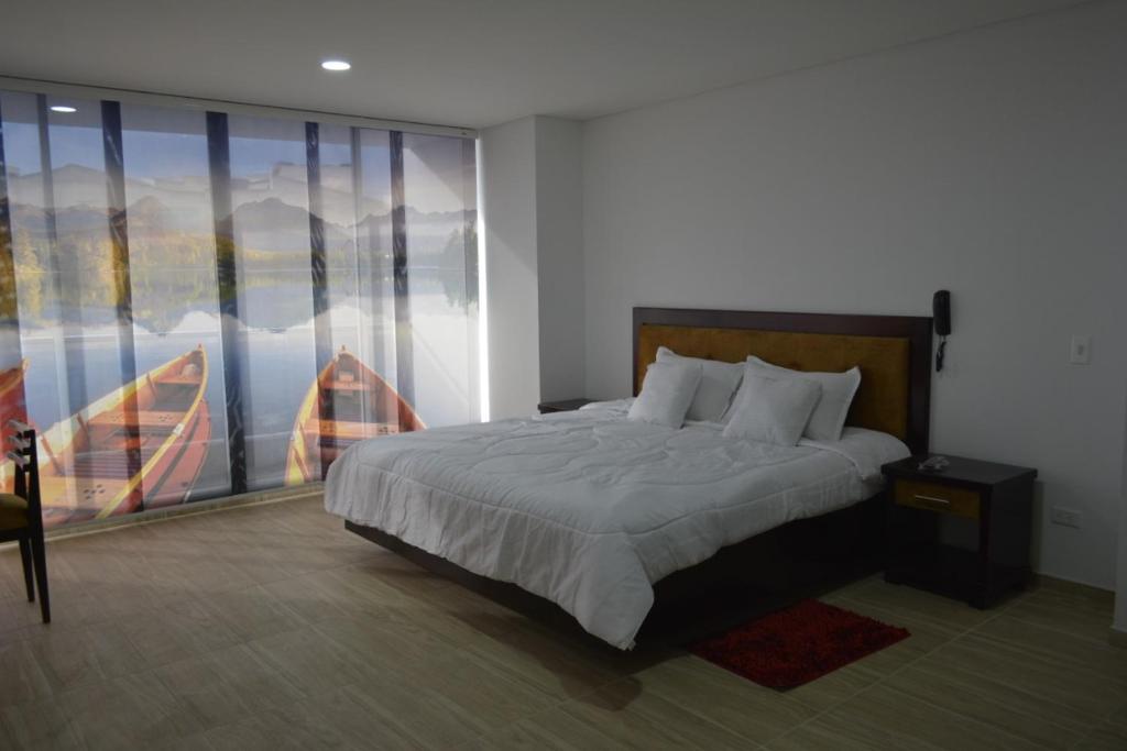 a bedroom with a large bed and a large window at Hotel Prestigio JC in Sogamoso