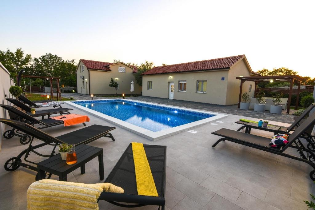 uma piscina com espreguiçadeiras e cadeiras num quintal em Apartments Gordana Mar - with pool em Vrsi