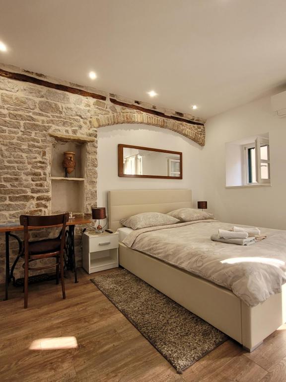 ein Schlafzimmer mit einem Bett und einem Schreibtisch mit einem Stuhl in der Unterkunft Sebenico Luxury Rooms in Šibenik