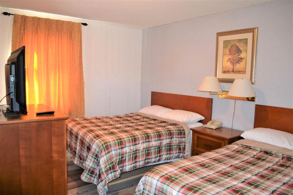 a hotel room with two beds and a flat screen tv at The Villager Motel in Burstall