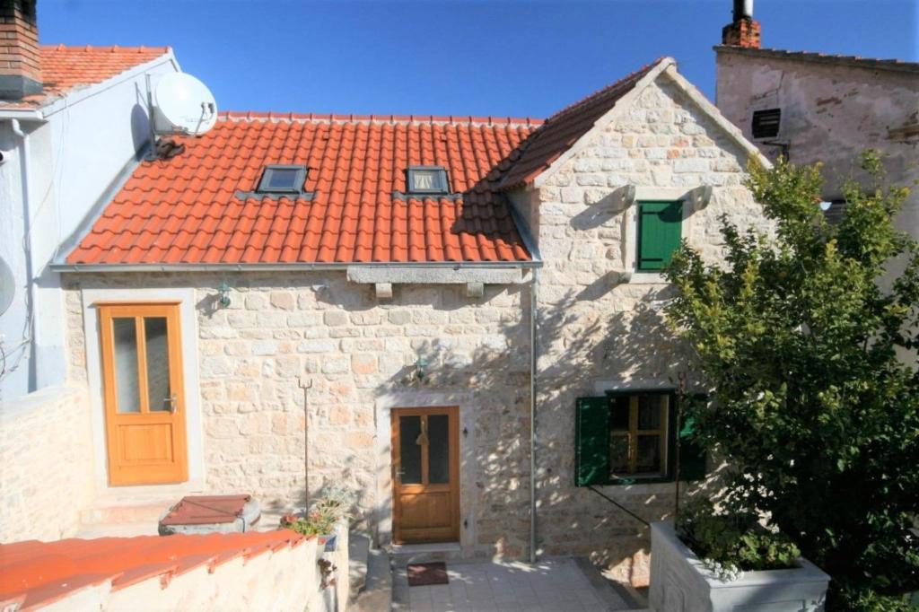 une ancienne maison en pierre avec un toit orange dans l'établissement Apt Draga - traditional & in center, à Vrboska