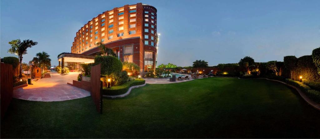 un grande edificio con un cortile verde di fronte a un edificio di Radisson Blu MBD Hotel Noida a Noida