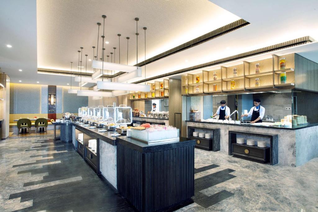 a restaurant with two chefs preparing food in a kitchen at Radisson Lampung Kedaton in Bandar Lampung