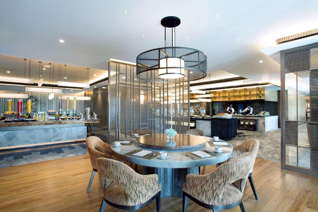 a dining room with a table and chairs and a kitchen at Radisson Lampung Kedaton in Bandar Lampung