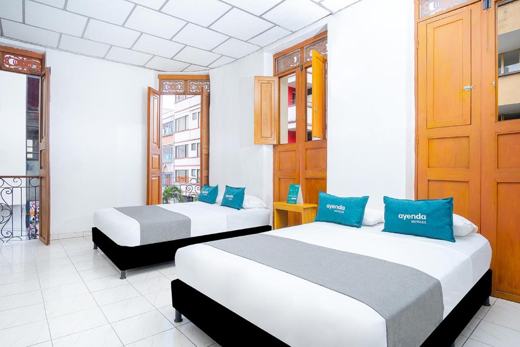 a room with two beds with blue pillows at Ayenda Acacia in Ibagué