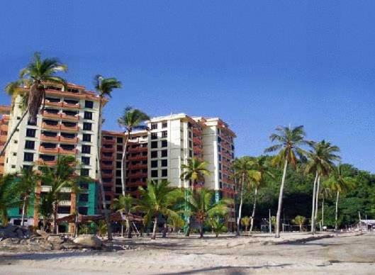 une plage avec des palmiers et de grands bâtiments dans l'établissement Marina Cove Resort, à Lumut