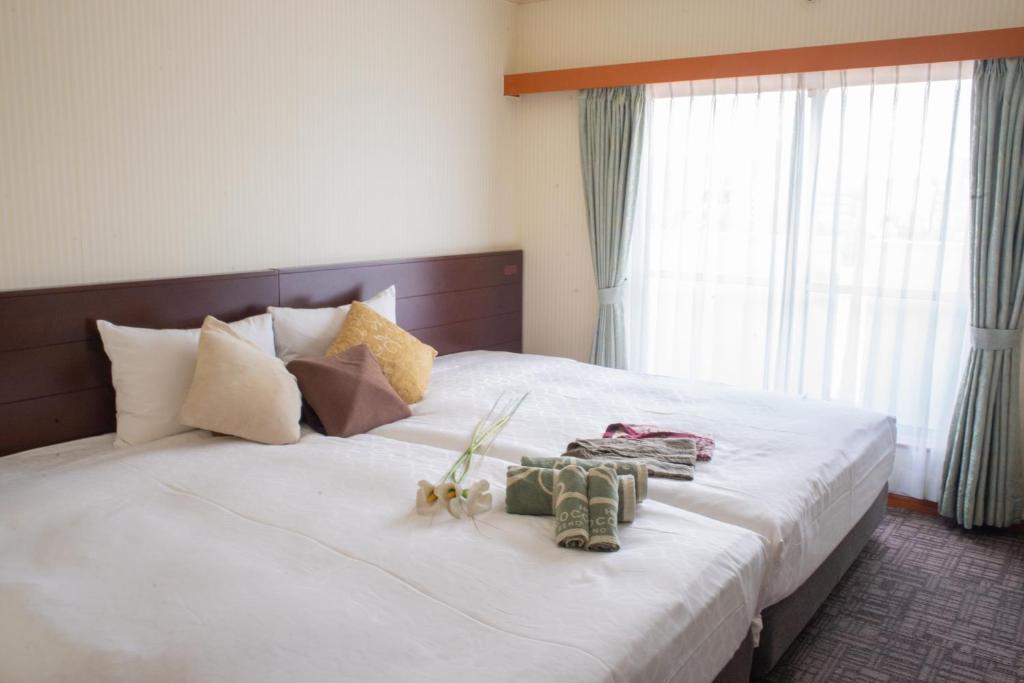 a bedroom with a large white bed with shoes on it at Outlet Hotel UenoEkimae in Tokyo